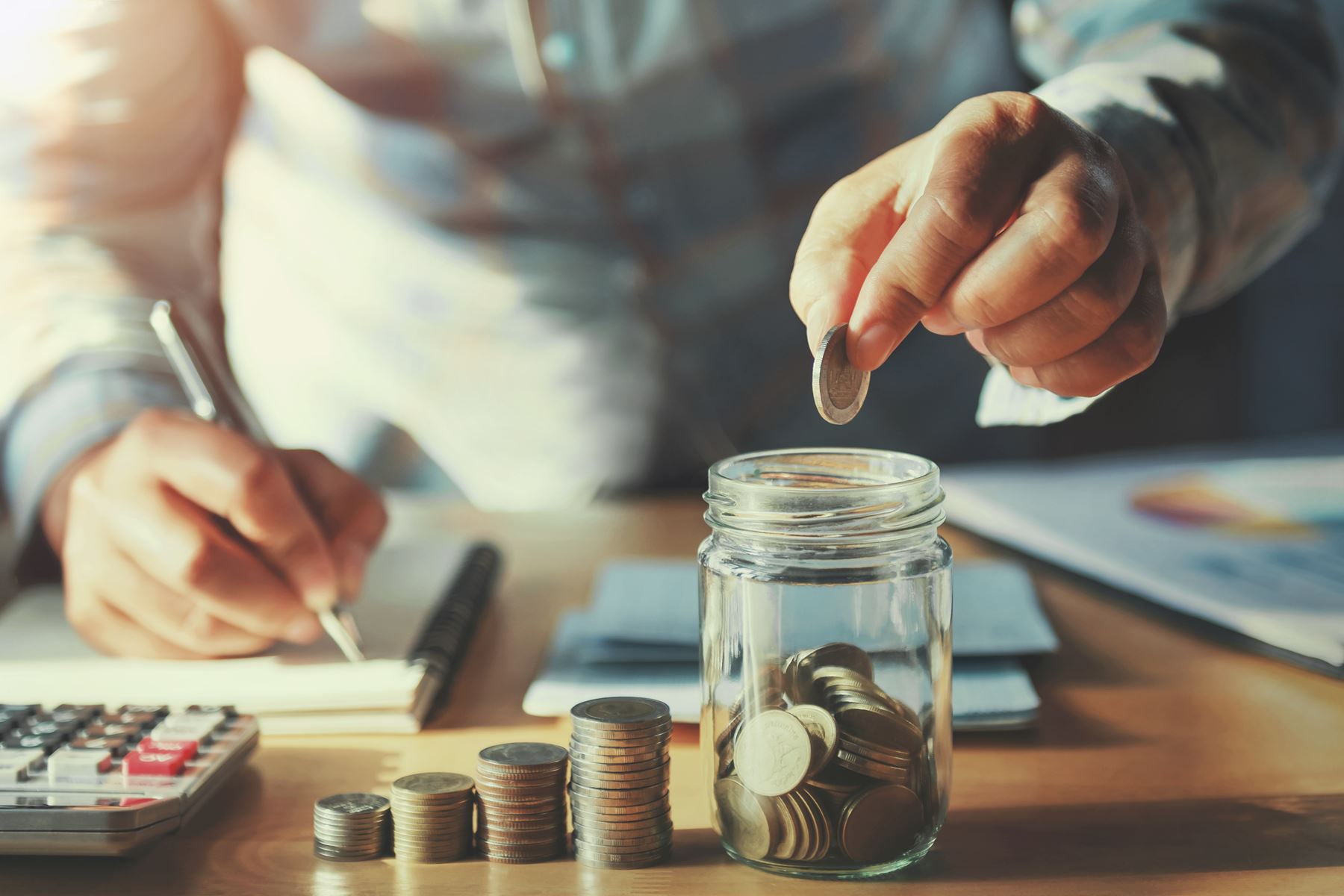 man putting coin in jar